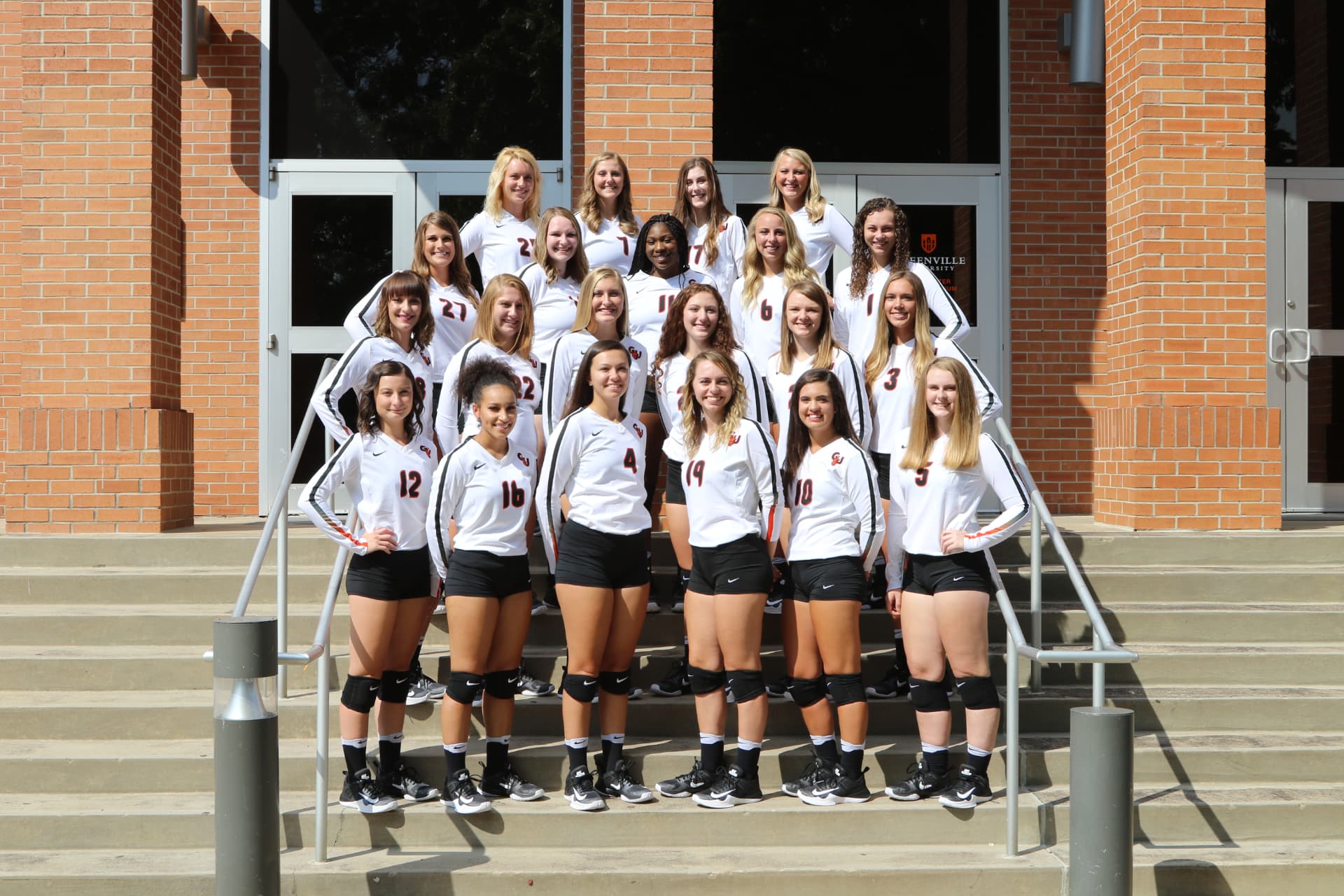 Greenville University women's volleyball team photo in warmups on the campus steps.