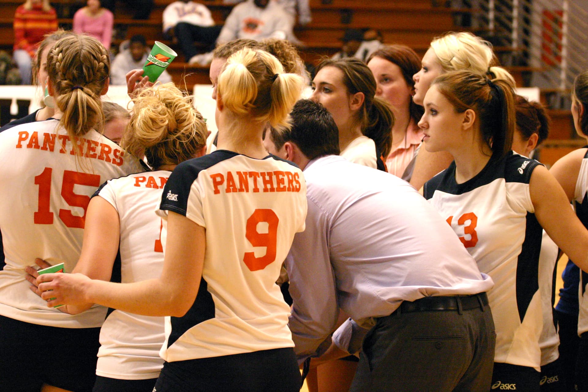 Greenville Panthers players in white jerseys huddled around their coach during a timeout.